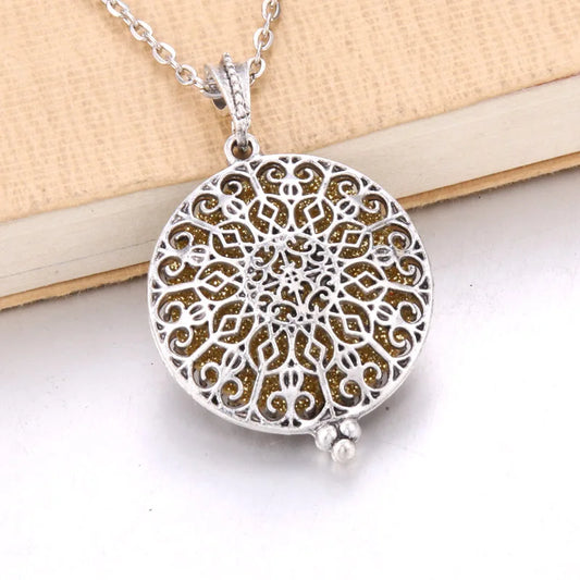Detaljbild på ett runt aromahalsband i silver med mandala-mönster.